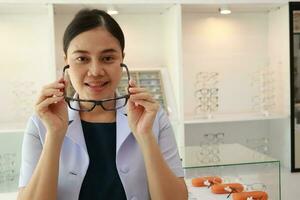 hembra oftalmólogo participación los anteojos dentro clínica, ojo médico participación lentes en los anteojos comercio, oftalmólogo participación los anteojos en lente clínica foto