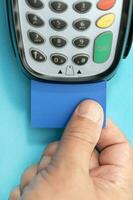 Hand put Credit card into payment terminal on blue background photo