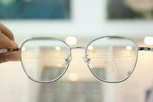 Hand holding eyeglass progressive lens in optical store photo