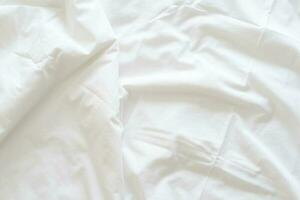 resumen modelo de blanco estropeado cama hoja. blanco arrugado tela textura ondulado superficie. cerca arriba. foto