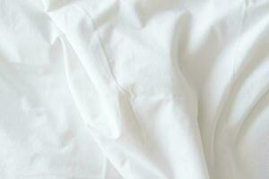 Abstract pattern of white crumpled bed sheet. White wrinkled fabric texture rippled surface. Close up. photo