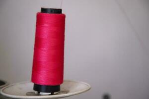 A Spool of red color swing thread with a Shallow depth of field photo