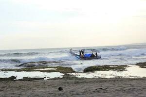 a boat with several fishermen crashing into the sea waves to catch fish. photo