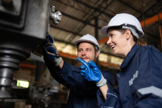 Both of mechanical engineers are checking the working condition of an old machine that has been used for some time. In a factory where natural light shines onto the workplace photo