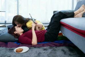 A forehead kiss is a sweet sign of affection for an LGBT couple relaxing in their living room on weekends photo