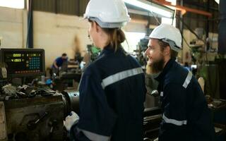 Both of mechanical engineers are checking the working condition of an old machine that has been used for some time. In a factory where natural light shines onto the workplace photo