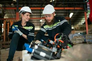 Both of engineers installing a small robotic arm is being installed for testing. before sending to customers for industrial use. photo