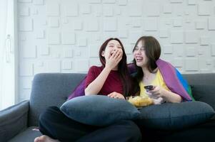 The LGBT couple watching a comedic drama on the sofa in the living room of their home. The couple laughed happily. photo