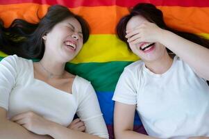 On a rainbow flag, an LGBT couple laughs cheerfully. photo