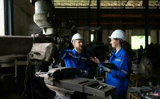Both of mechanical engineers are checking the working condition of an old machine that has been used for some time. In a factory where natural light shines onto the workplace photo