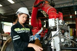 Female electrical engineer with the mission of installing a robot arm electrical system photo