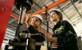 Both of mechanical engineers are checking the working condition of the new machine after completing the installation photo