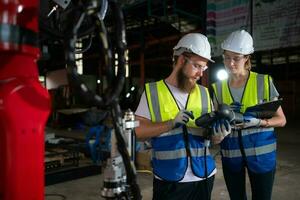 Both of engineers installing and testing a large robotic arm. before sending it to customers for use in the industry photo