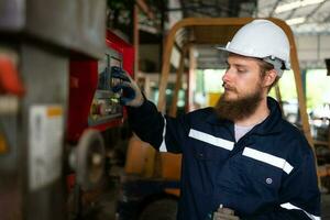 Portrait of mechanical engineers are checking the working condition of an old machine that has been used for some time. In a factory where natural light shines onto the workplace photo