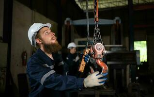 Two technicians inspecting and testing the operation of lifting cranes in heavy industrial plants. photo