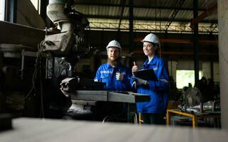 Both of mechanical engineers are checking the working condition of an old machine that has been used for some time. In a factory where natural light shines onto the workplace photo