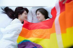 In a hotel bedroom, an LGBT couple snuggled together on the bed happily. photo