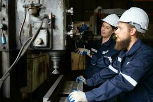 Both of mechanical engineers are checking the working condition of an old machine that has been used for some time. In a factory where natural light shines onto the workplace photo