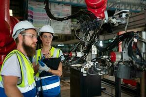 ambos de ingenieros instalando y pruebas un grande robótico brazo. antes de enviando eso a clientes para utilizar en el industria foto