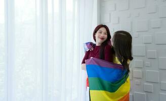 LGBT couples cover rainbow flags around their loved ones to keep warm and gaze out their hotel room windows together. photo