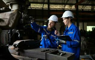 Both of mechanical engineers are checking the working condition of an old machine that has been used for some time. In a factory where natural light shines onto the workplace photo