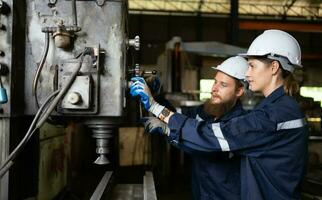 Both of mechanical engineers are checking the working condition of an old machine that has been used for some time. In a factory where natural light shines onto the workplace photo