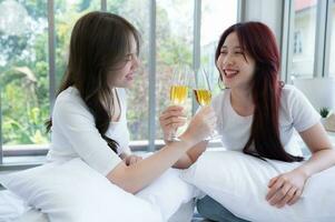 The LGBT couple celebrating with a glass of wine In a hotel room surrounded by nature photo