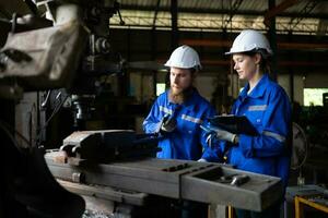 Both of mechanical engineers are checking the working condition of an old machine that has been used for some time. In a factory where natural light shines onto the workplace photo