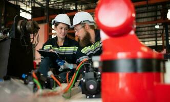 Both of engineers installing a small robotic arm is being installed for testing. before sending to customers for industrial use. photo