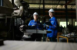 Both of mechanical engineers are checking the working condition of an old machine that has been used for some time. In a factory where natural light shines onto the workplace photo