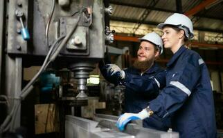 Both of mechanical engineers are checking the working condition of an old machine that has been used for some time. In a factory where natural light shines onto the workplace photo