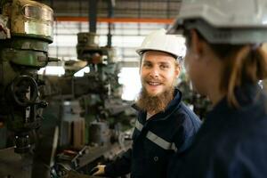 Both of mechanical engineers are checking the working condition of an old machine that has been used for some time. In a factory where natural light shines onto the workplace photo