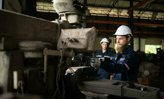 Portrait of mechanical engineers are checking the working condition of an old machine that has been used for some time. In a factory where natural light shines onto the workplace photo