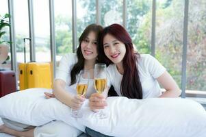 The LGBT couple celebrating with a glass of wine In a hotel room surrounded by nature photo