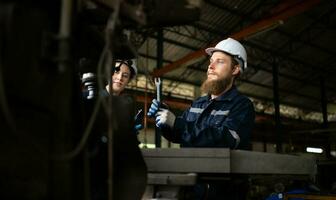 Portrait of mechanical engineers are checking the working condition of an old machine that has been used for some time. In a factory where natural light shines onto the workplace photo