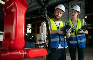 ambos de ingenieros instalando y pruebas un grande robótico brazo. antes de enviando eso a clientes para utilizar en el industria foto