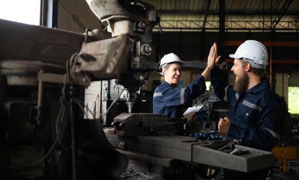 Both of mechanical engineers are checking the working condition of an old machine that has been used for some time. In a factory where natural light shines onto the workplace photo