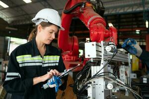 Female electrical engineer with the mission of installing a robot arm electrical system photo