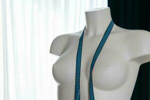 White modern mannequin or dressmakers dummy with hanging measuring tape, closeup photo