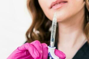 Close-up of female beautician doctor holding syringe with beauty injections photo