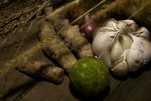 Shallotred union, garlic , lime and turmeric on wooden background. photo