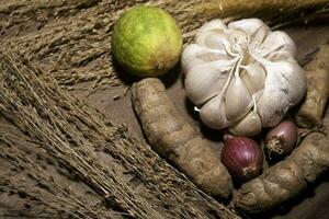 Shallotred union, garlic , lime and turmeric on wooden background. photo