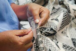 Close up photo of a woman's hands sewing batik cloth in Indonesia