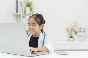 Cute little girl wearing doctor's coat using laptop photo