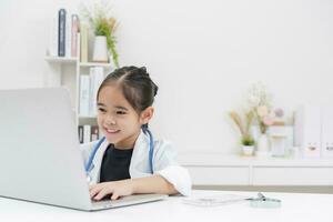 Cute little girl wearing doctor's coat using laptop photo