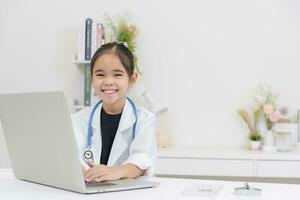 Cute little girl wearing doctor's coat using laptop photo