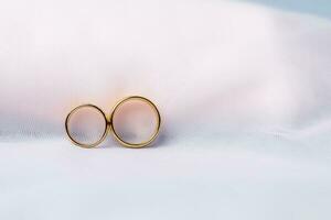 Golden wedding rings for engagement. Marriage golden rings with white, pink ribbons background. Rings on the white and red rose. The marriage rings is the symbol of traditional wedding of pair lovers. photo