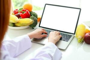 asiático hembra médico o nutricionista utilizar un ordenador portátil para en línea vídeo llamadas dar Consejo a el paciente acerca de alimento. en línea paciente salud cuidado concepto sano comiendo. peso pérdida. blanco pantalla. foto