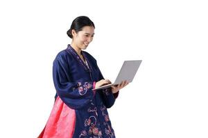 Beautiful Asian woman wearing hanbok, the national dress of Korea. Standing holding a laptop on a white background. isolated. Clipping path photo