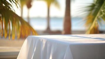 Empty wooden table with white tablecloth for product display on sea beach blurred background. photo